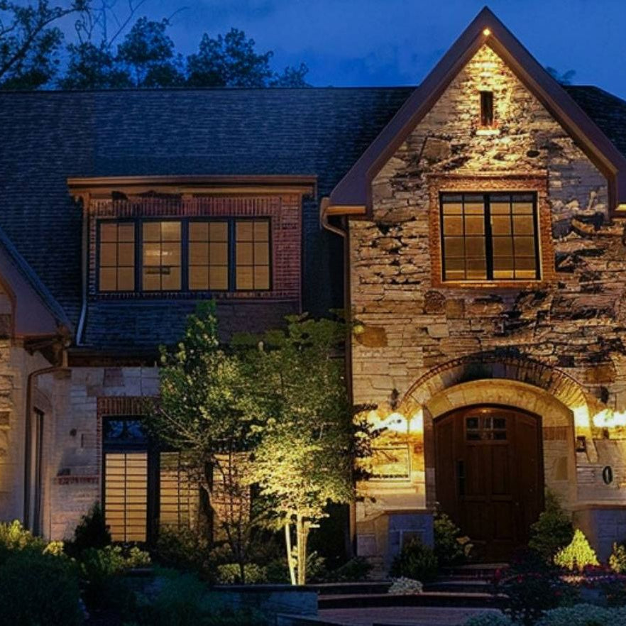 House exterior with low-voltage outdoor spotlights uplighting the stone facade at night